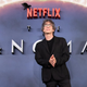 Neil Gaiman in front of the Sandman logo.
